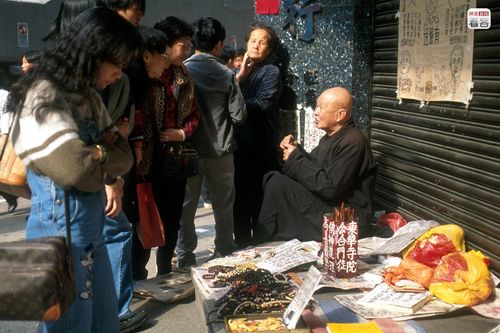 图为2002年4月17日,香港街头的算命先生在为路人